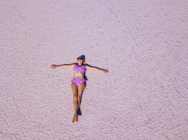 Güzel seksi kız pembe bir tuzlu göl üzerinde poz bir pembe mayo içinde. Photoshoot tuzlu bir pembe göl bir tabaklanmış kız.