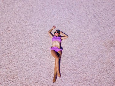 Güzel seksi kız pembe bir tuzlu göl üzerinde poz bir pembe mayo içinde. Photoshoot tuzlu bir pembe göl bir tabaklanmış kız.