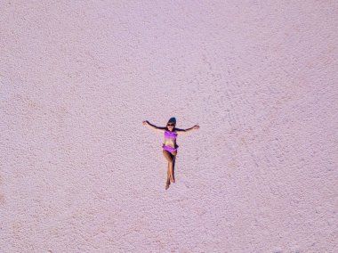 Güzel seksi kız pembe bir tuzlu göl üzerinde poz bir pembe mayo içinde. Photoshoot tuzlu bir pembe göl bir tabaklanmış kız.