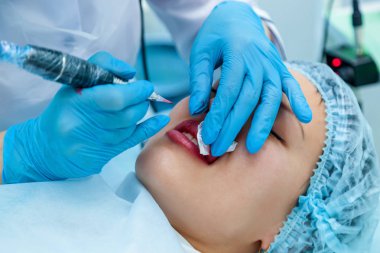 Güzellik uzmanı, dudaklarından kalıcı makyaj uygulanır. Dudak dövme