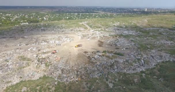 市は黄色の家の近くの街の郊外にダンプします ブルドーザーは埋め立て地に沿って移動し ゴミをレベリングします 食物廃棄物を餌とするカモメが飛び立つ — ストック動画