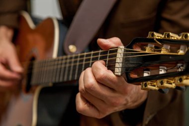 Gitar çalan bir müzisyenin ellerinin yakın çekimi. Gitarın tellerine müzisyenin parmakları basıyor. Bas gitar çalan müzisyen