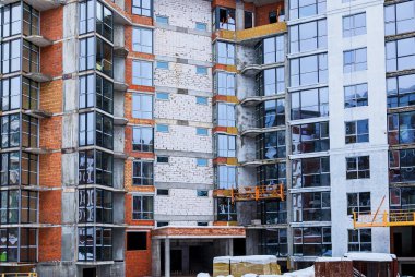 Yüksek katlı bir binadaki apartmanların cam ön cephesi. Modern bir binanın tasarımında pencere ve balkonlar.