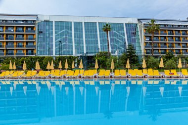 sarı şezlonglu mavi yüzme havuzu