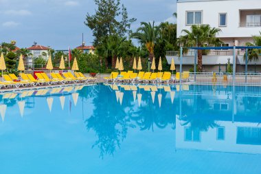 sarı şezlonglu mavi yüzme havuzu