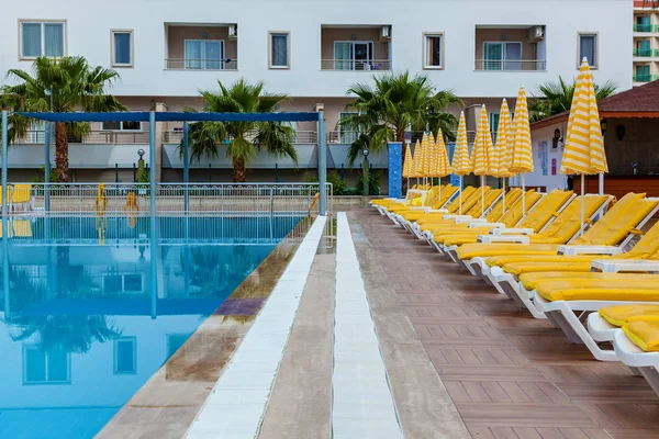 Blue swimming pool with yellow loungers — Stock Photo, Image