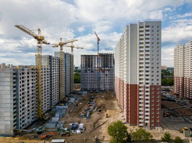 Çok katlı binalar, kule vinçleri ve inşaat ekipmanları olan bir inşaat alanı. Yüksek binaların inşaatı