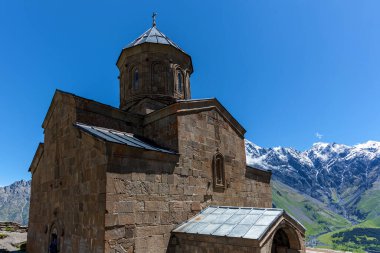 Dağdaki Trinity Kilisesi, Gürcistan Askeri Otoyolu 'ndaki Gergeti köyündeki kayaların arka planına karşı.