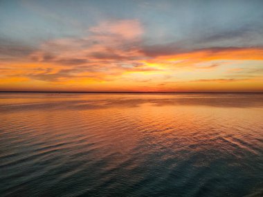 Güneş battıktan sonra, deniz aynasından yansıyan kırmızı ve sarı ışık.