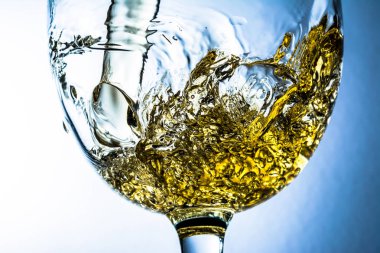 Beyaz şarap bir bardak dökme, gri arka plan üzerinde beyaz şarap sıçrama akış. Parlak görünüm fotoğraf.