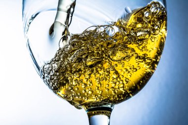 Beyaz şarap bir bardak dökme, gri arka plan üzerinde beyaz şarap sıçrama akış. Parlak görünüm fotoğraf.