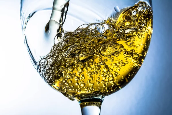 Beyaz şarap bir bardak dökme, gri arka plan üzerinde beyaz şarap sıçrama akış. Parlak görünüm fotoğraf.