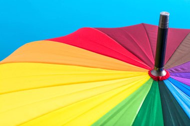 Mavi bir arka plan üzerinde gökkuşağının bütün renkleri ile çok renkli renkli şemsiye. Parlak doku arka plan.