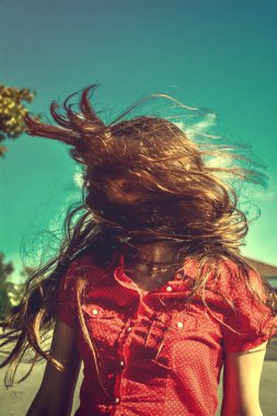 Güneş ışığı altında rüzgarda çırpınan uzun saçlı Genç bir kız. Uzun saçlı Genç bir kız mavi gökyüzü arka plan üzerinde güneş ışınlarının başını sallıyor. Vintage, grunge, retro tarzı fotoğraf.