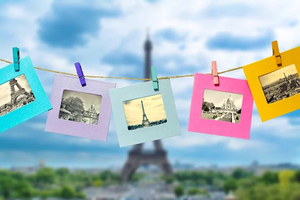 Old photos of the main attractions of Paris in a fun framework, attached with a clothes-peg clothespin to the hanging lashing rope against the backdrop of the panorama of Paris with the Eiffel Tower.