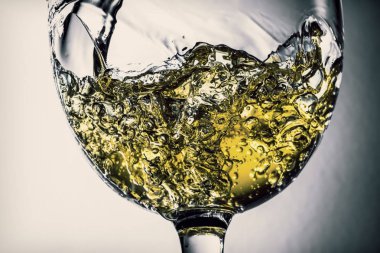 Beyaz şarap bir bardak beyaz şarap gri bir arka plan üzerinde sıçrama yakın çekim içine dökme akışı. Şarap rengi ile siyah ve beyaz fotoğraf. Vintage, grunge, eski, retro tarzı.