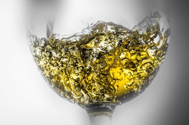 Beyaz şarap bir bardak beyaz şarap gri bir arka plan üzerinde sıçrama yakın çekim içine dökme akışı. Siyah ve beyaz fotoğraf rengine etrafında güzel sis ve şarap ile