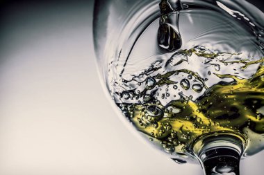 Beyaz şarap bir bardak beyaz şarap gri bir arka plan üzerinde sıçrama yakın çekim içine dökme akışı. Şarap rengi ile siyah ve beyaz fotoğraf. Vintage, grunge, eski, retro tarzı.