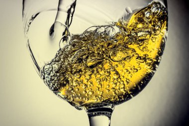 Beyaz şarap bir bardak beyaz şarap gri bir arka plan üzerinde sıçrama yakın çekim içine dökme akışı. Şarap rengi ile siyah ve beyaz fotoğraf. Vintage, grunge, eski, retro tarzı.