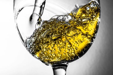 Beyaz şarap bir bardak beyaz şarap gri bir arka plan üzerinde sıçrama yakın çekim içine dökme akışı. Şarap rengi ile siyah ve beyaz fotoğraf.