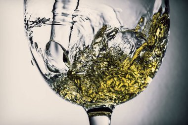 Beyaz şarap bir bardak beyaz şarap gri bir arka plan üzerinde sıçrama yakın çekim içine dökme akışı. Şarap rengi ile siyah ve beyaz fotoğraf. Vintage, grunge, eski, retro tarzı.