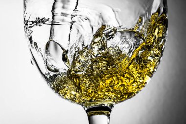 Beyaz şarap bir bardak beyaz şarap gri bir arka plan üzerinde sıçrama yakın çekim içine dökme akışı. Şarap rengi ile siyah ve beyaz fotoğraf.