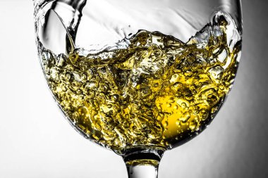 Beyaz şarap bir bardak beyaz şarap gri bir arka plan üzerinde sıçrama yakın çekim içine dökme akışı. Şarap rengi ile siyah ve beyaz fotoğraf.