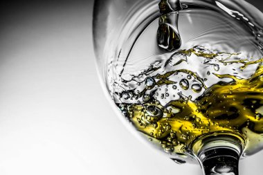 Beyaz şarap bir bardak beyaz şarap gri bir arka plan üzerinde sıçrama yakın çekim içine dökme akışı. Şarap rengi ile siyah ve beyaz fotoğraf.