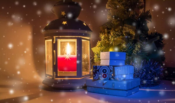 圣诞树与礼品盒和古老的老式灯笼与燃烧的蜡烛和一个美丽的光芒作为明星在下降的雪和雪花背景 — 图库照片