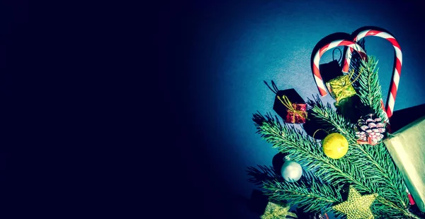 Topları, çam kozalakları, geleneksel şeker ve wodden arka plan üzerinde hediye kutuları ile bir Noel ağacı dalı. Noel ve yeni yıl arka plan metin için boş alan ile.