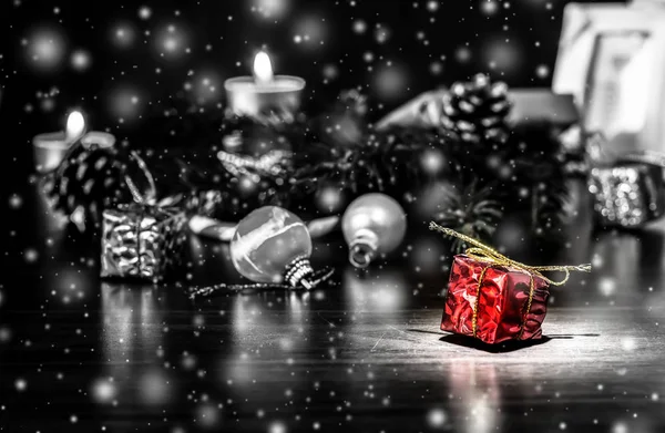 新年礼物在红色包装与金弓在黑色和白色的圣诞节背景与下降的雪 圣诞节假期仍然生活与美丽的下降雪 — 图库照片