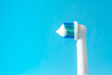 Mavi bir arka plan üzerine diş macunu closeup ile elektrikli diş fırçası