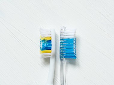 Vintage beyaz bir arka plan üzerinde yeni ve yoğun olarak kullanılan diş fırçaları yakın çekim.