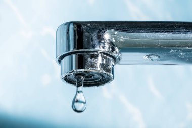 Bir damla su asmak dışarı bir modern krom kaplama su musluk musluk makro yakın çekim.
