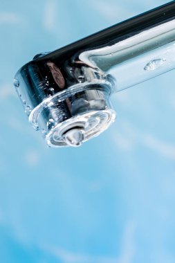 Bir damla su asmak dışarı bir modern krom kaplama su musluk musluk makro yakın çekim.