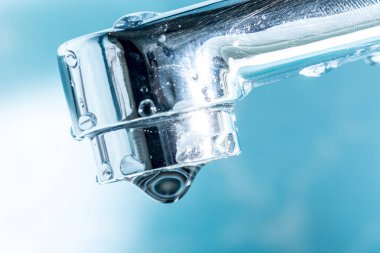 Bir damla su asmak dışarı bir modern krom kaplama su musluk musluk makro yakın çekim.