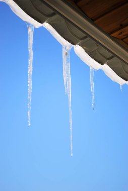 Mavi açık gökyüzü güneş ışınlarının çatı asılı buz sarkıtları