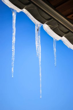 Mavi açık gökyüzü güneş ışınlarının çatı asılı buz sarkıtları