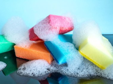 Mavi bir arka plan üzerinde köpük ve yansıma yakın çekim ile renkli süngerler