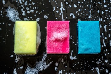 Siyah cam arka plan üzerinde köpük yakın çekim ile renkli süngerler