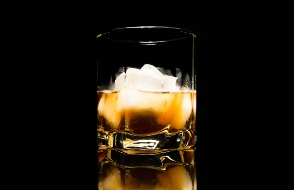在黑色背景上被隔离的玻璃桌子上, 有冰的威士忌 — 图库照片