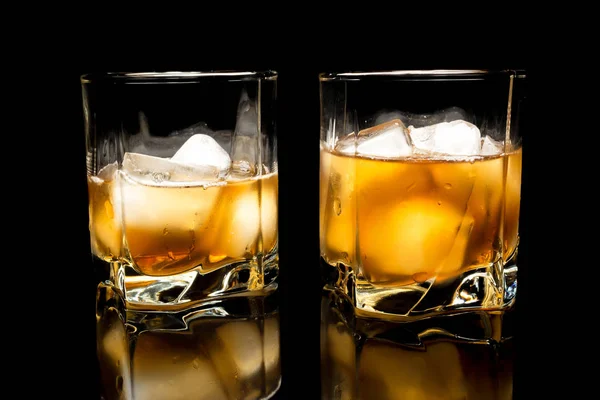 Whiskyt jéggel közelről egy üveg asztal fekete alapon elszigetelt — Stock Fotó