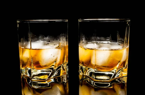 Whiskey with ice close up on a glass table isolated on a black background — Stock Photo, Image