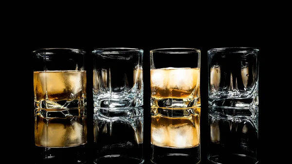 Whiskey with ice close up on a glass table isolated on a black background — Stock Photo, Image