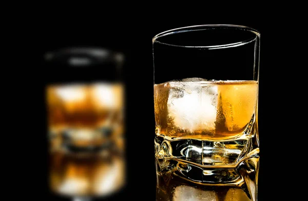 Buzlu viski yakın çekim üzerinde siyah bir arka plan üzerinde izole bir cam masa — Stok fotoğraf