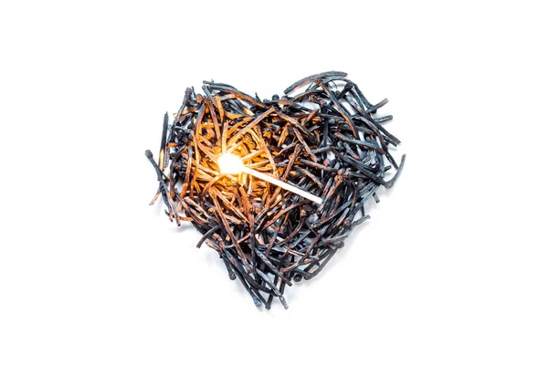 Το σύμβολο της καρδιάς φτιαγμένο από καμμένα σπίρτα κοντά σε ένα φλεγόμενο σπίρτο στο κέντρο, απομονωμένο σε λευκό φόντο. Η έννοια της πολυπλοκότητας των σχέσεων αγάπης, η δυστυχισμένη αγάπη. — Φωτογραφία Αρχείου