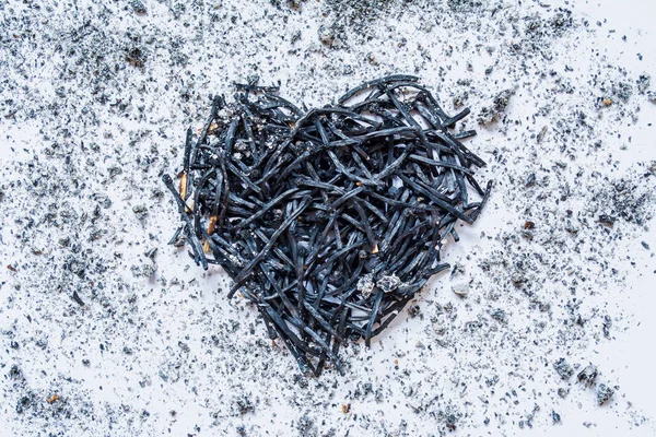 Heart symbol made of burned-down matches close-up with ashes around. The concept of the complexity of love relationships, unhappy love. — Stock Photo, Image