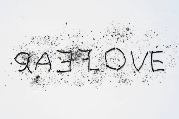 The words love and hate close-up, lined mirror of burnt down matches with ashes around on a white background. The concept of the complexity of love relationships, unhappy love.