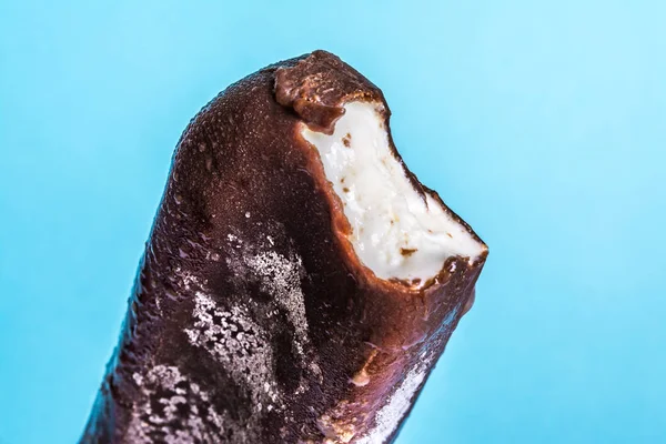 Lolly helado mordido en esmalte de chocolate primer plano con condensado y heladas de hielo sobre un fondo de cielo azul de verano. Textura de helado . —  Fotos de Stock