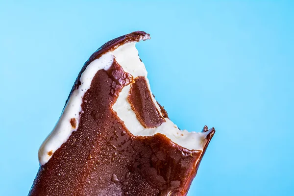 Gelato morso lecca lecca in primo piano smalto di cioccolato con condensa e gelata glassa su uno sfondo cielo blu estivo. Texture gelato . — Foto Stock